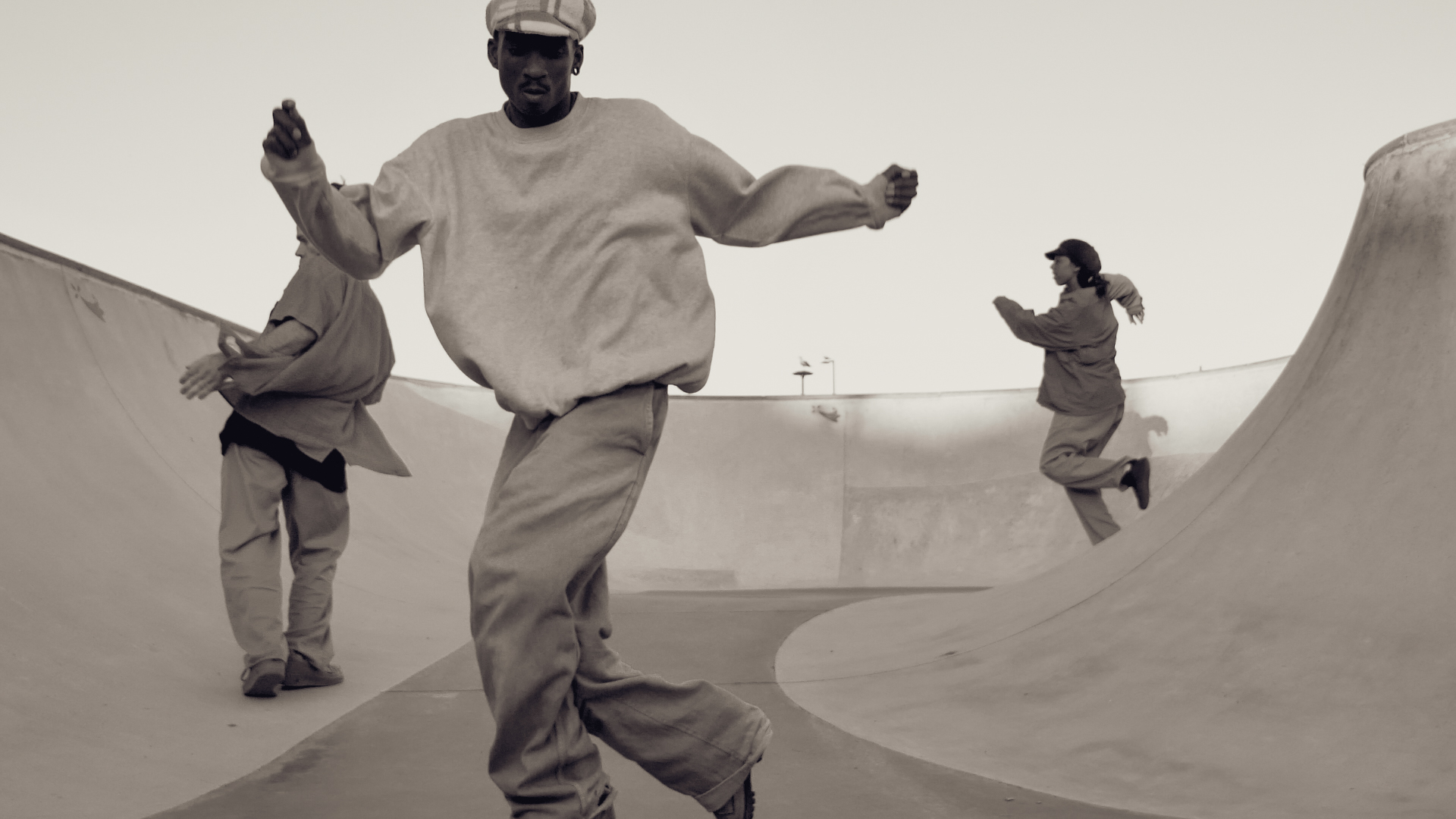 Trois danseurs et danseuses en mouvement dans le bol en béton d'un skatepark